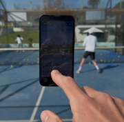 Rally360 phone mount attached to padel court glass with court view